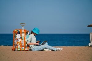 girl remote worker sits on the beach with a suitcase and works while on vacation