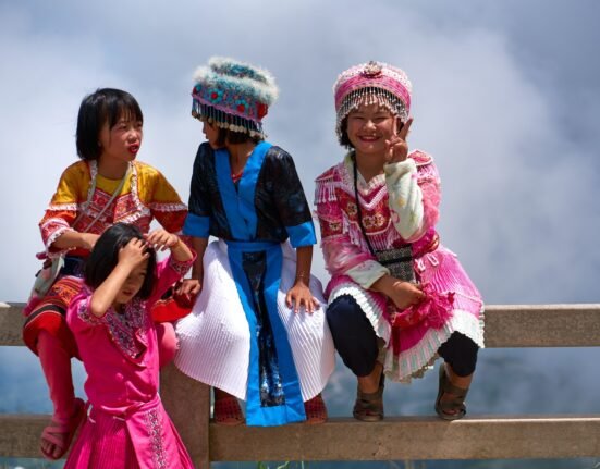 a group of young girls sitting on top of a wooden bench