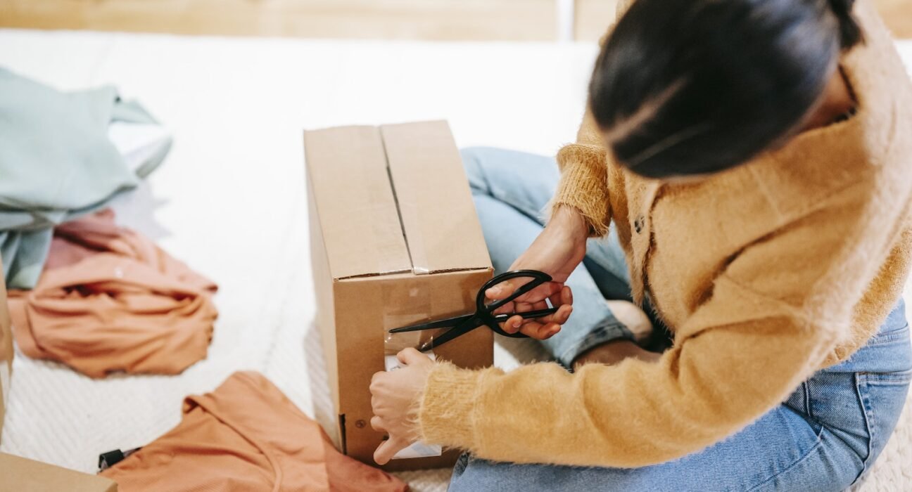 Woman cutting off adhesive tape from box with parcel