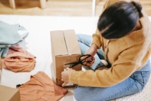 Woman cutting off adhesive tape from box with parcel