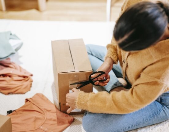 Woman cutting off adhesive tape from box with parcel