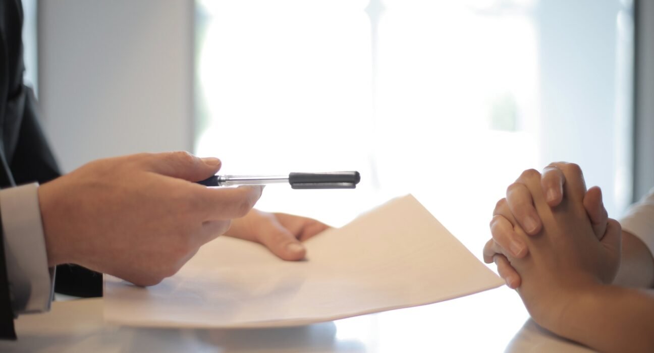 Crop businessman giving contract to woman to sign