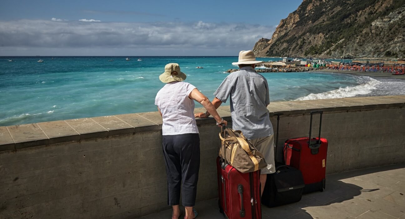 man and woman standing beside concrete seawall looking at beach