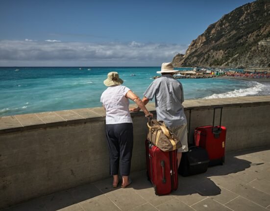 man and woman standing beside concrete seawall looking at beach