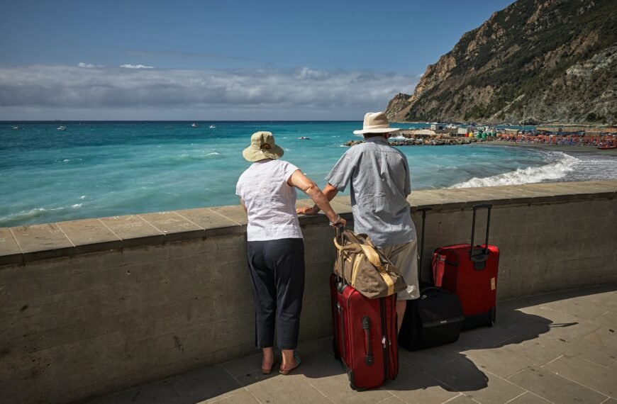 man and woman standing beside concrete seawall looking at beach