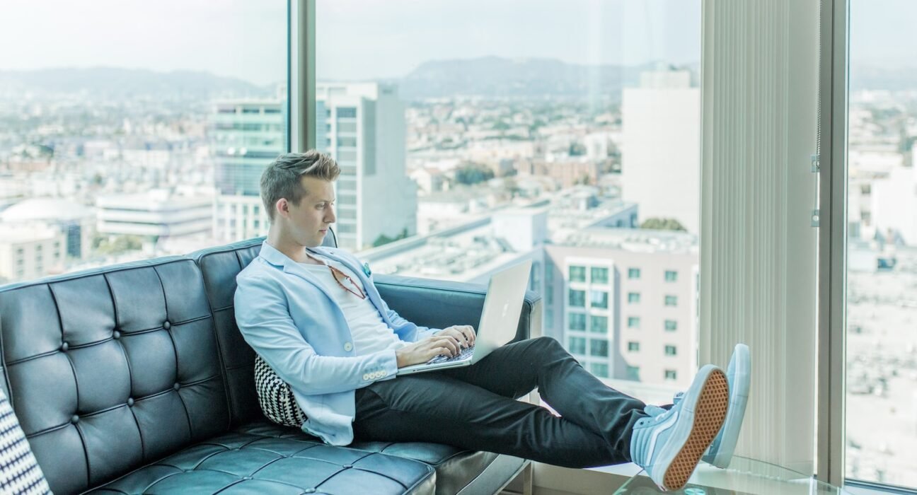 man sitting on sofa while using laptop