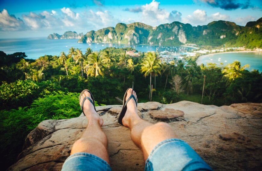 person wearing black flip-flops sitting on rock