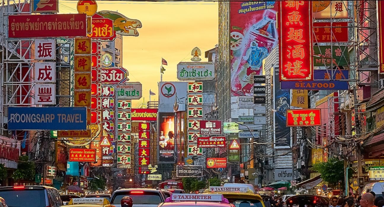 vehicles on street between buildings with Kanji script signage during golden hour