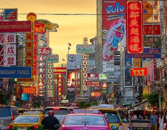 vehicles on street between buildings with Kanji script signage during golden hour