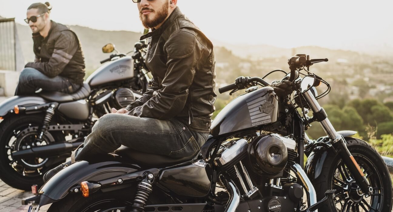 two men sitting on two parked cruiser motorcycles