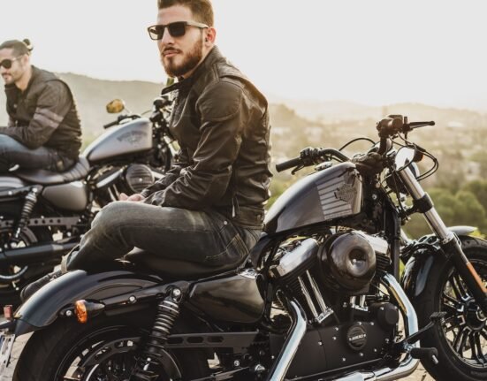 two men sitting on two parked cruiser motorcycles