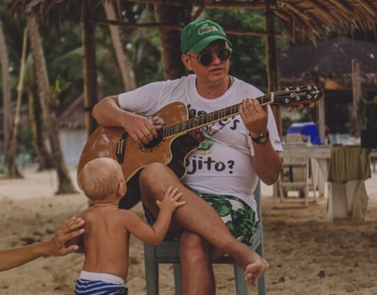 man sitting on chair while playing guitar