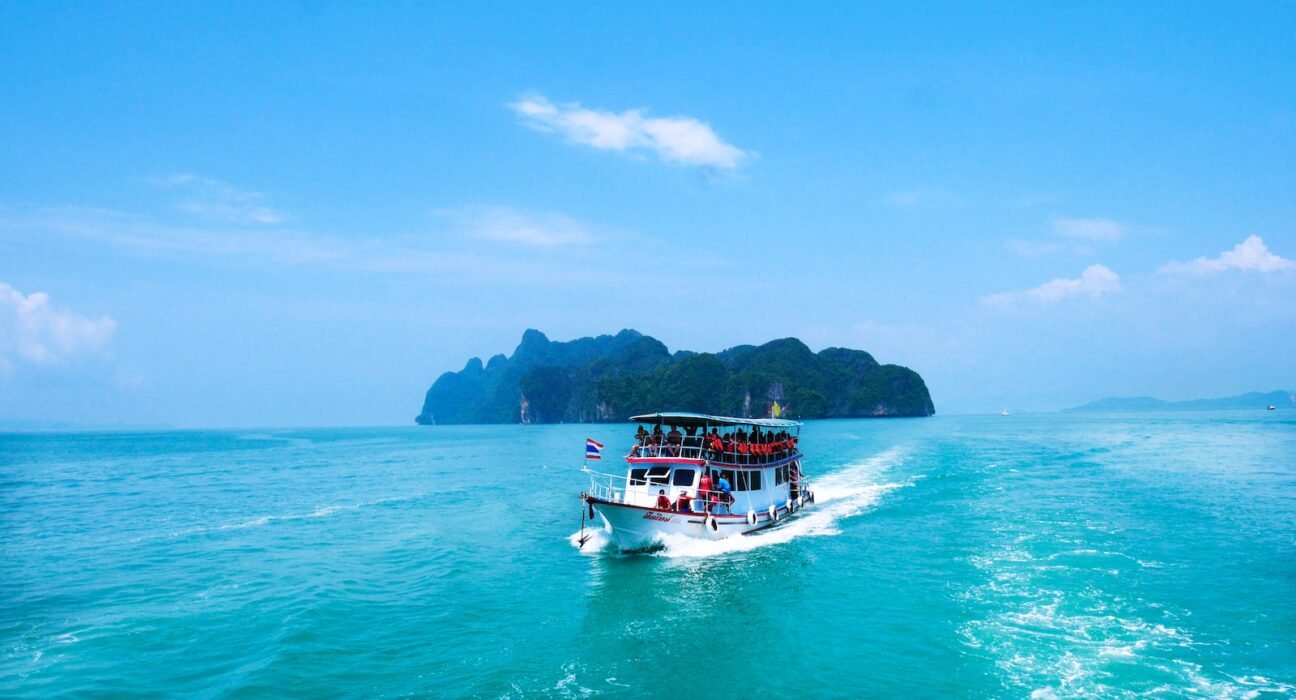 boat with peoples sailing on body of water with island background