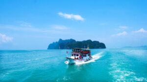boat with peoples sailing on body of water with island background