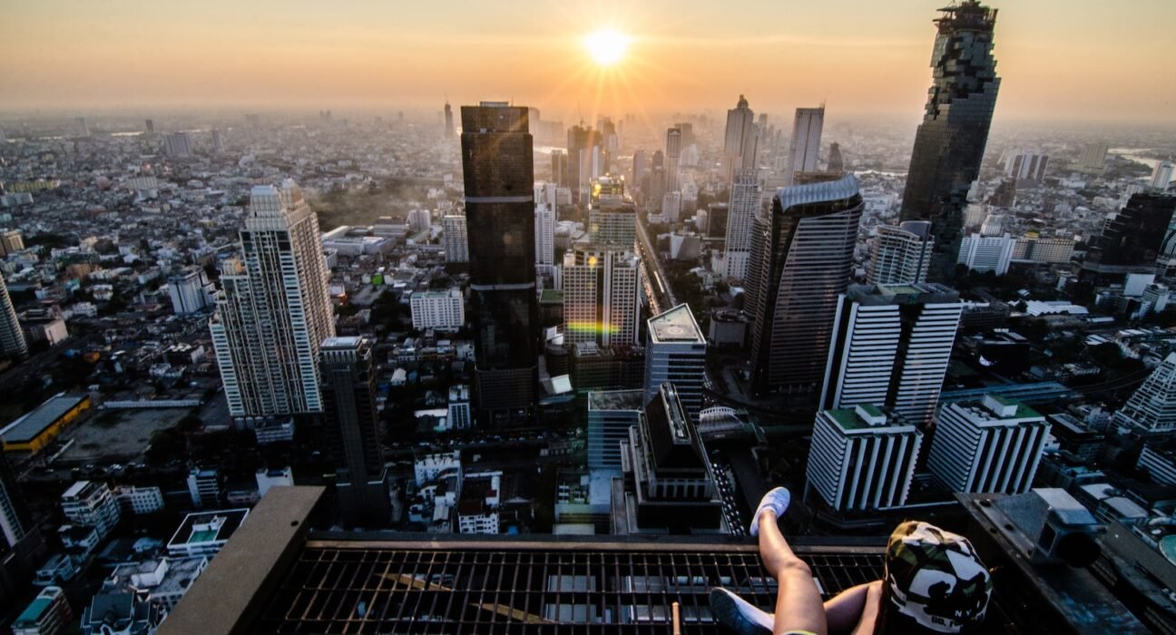 a person sitting on a ledge overlooking a city