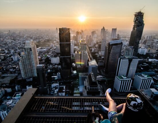 a person sitting on a ledge overlooking a city