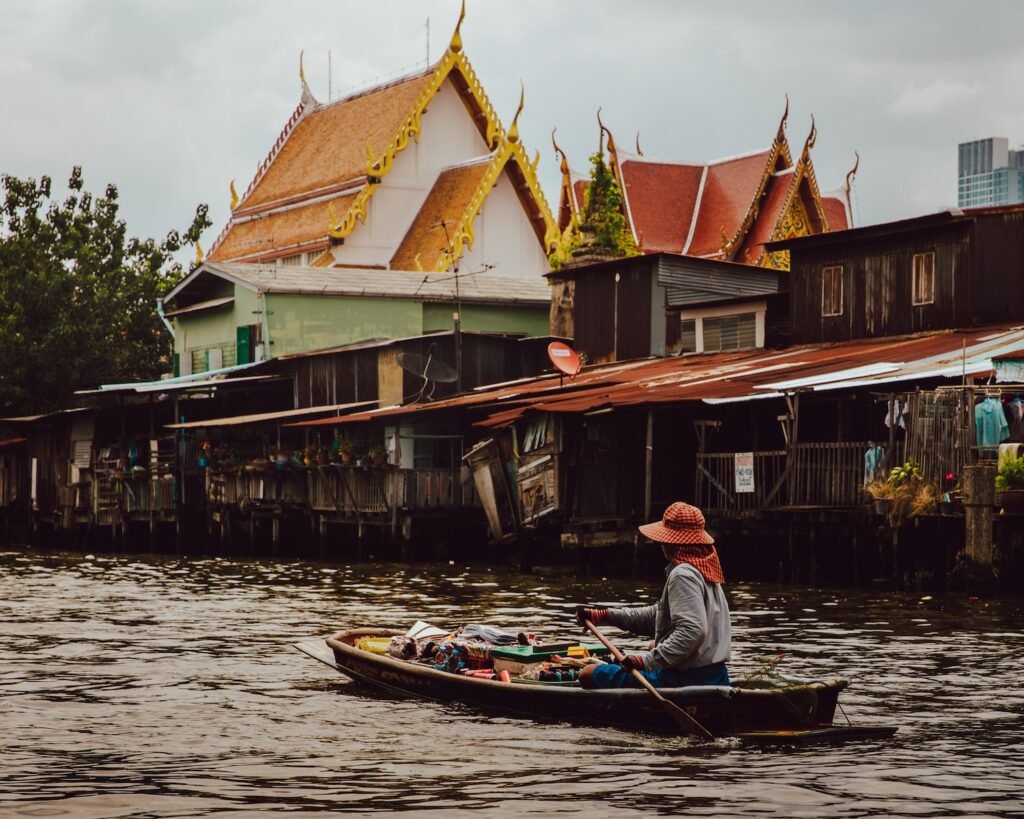 woman riding boat holding paddle on calm body of water in front of houses