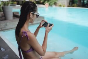 Fit woman chilling on poolside and taking picture of legs