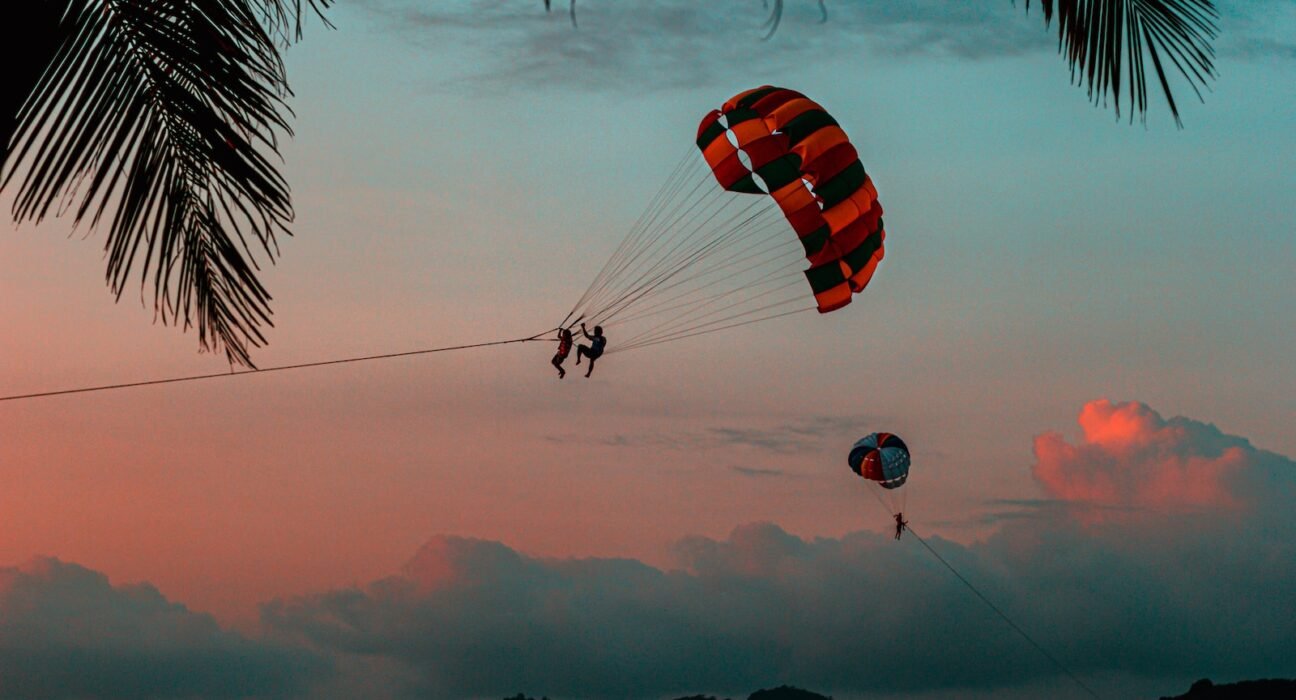 silhouette of 2 person riding parachute during sunset