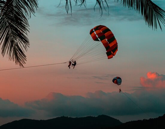 silhouette of 2 person riding parachute during sunset