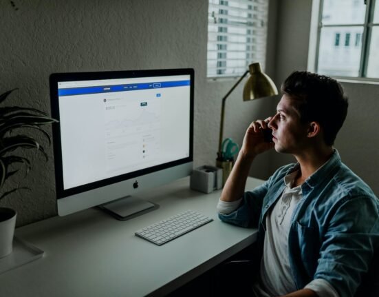 man in blue denim jacket facing turned on monitor
