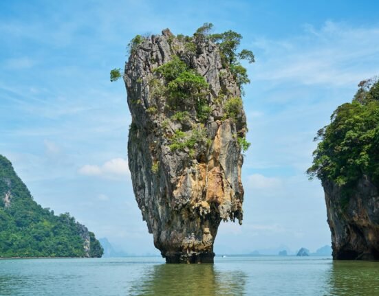 brown rock formation on body of water during daytime