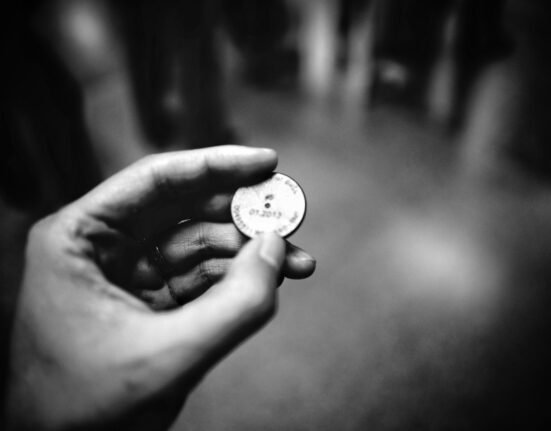 grayscale photography of person holding coin