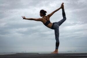 woman in black sports bra and blue leggings doing yoga during daytime