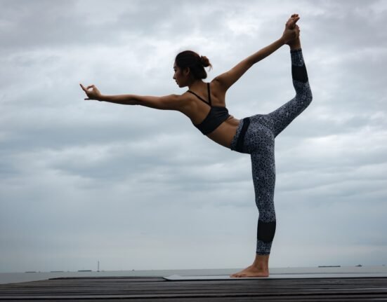 woman in black sports bra and blue leggings doing yoga during daytime