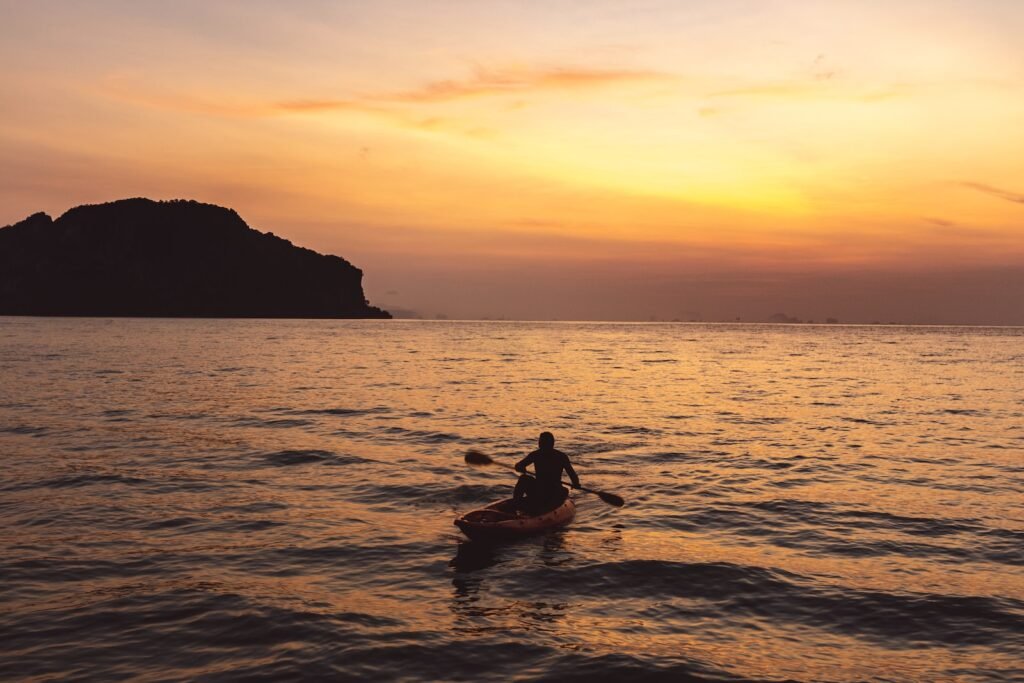 silhouette of man riding on boat during sunset