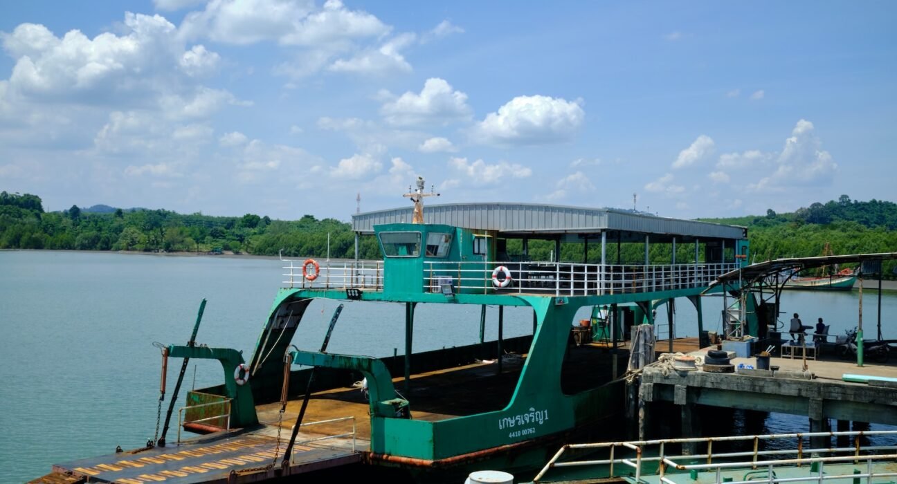 a green ferry boat docked at a pier