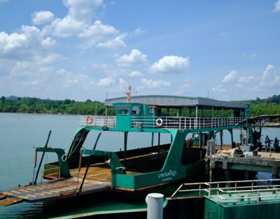 a green ferry boat docked at a pier
