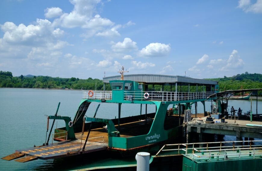 a green ferry boat docked at a pier