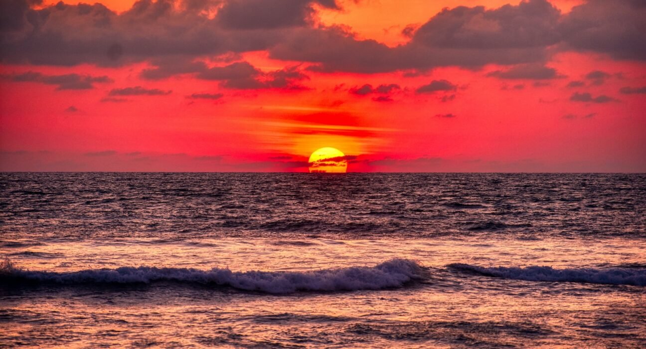 ocean waves crashing on shore during sunset