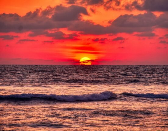 ocean waves crashing on shore during sunset