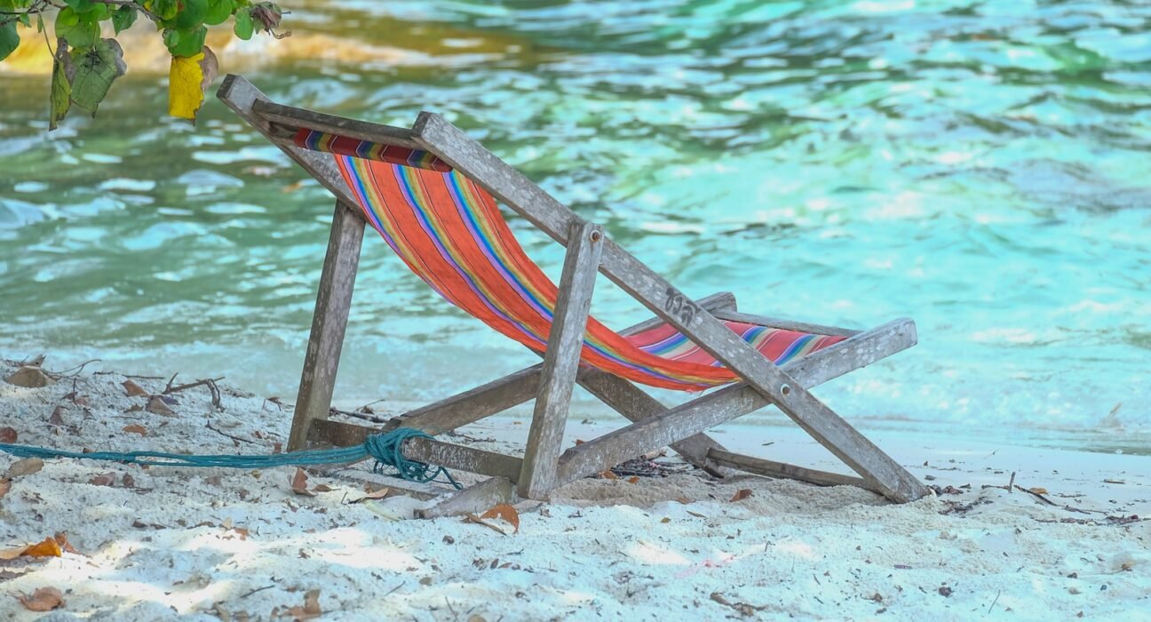 red and blue striped folding chair on beach shore during daytime