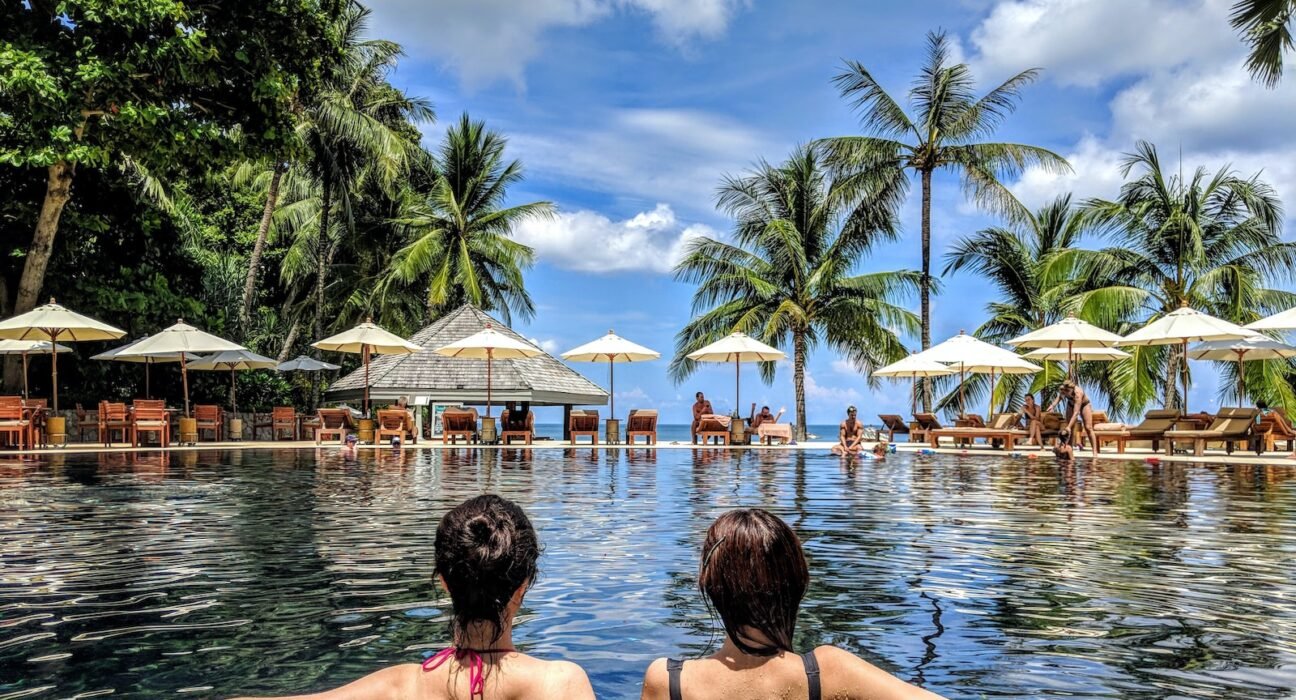 two woman leaning on inground pool tile