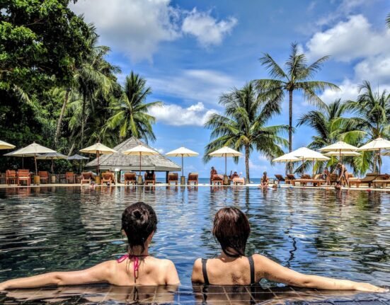 two woman leaning on inground pool tile