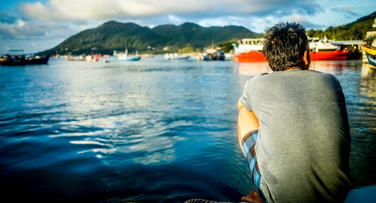 man sitting on boat in body of water