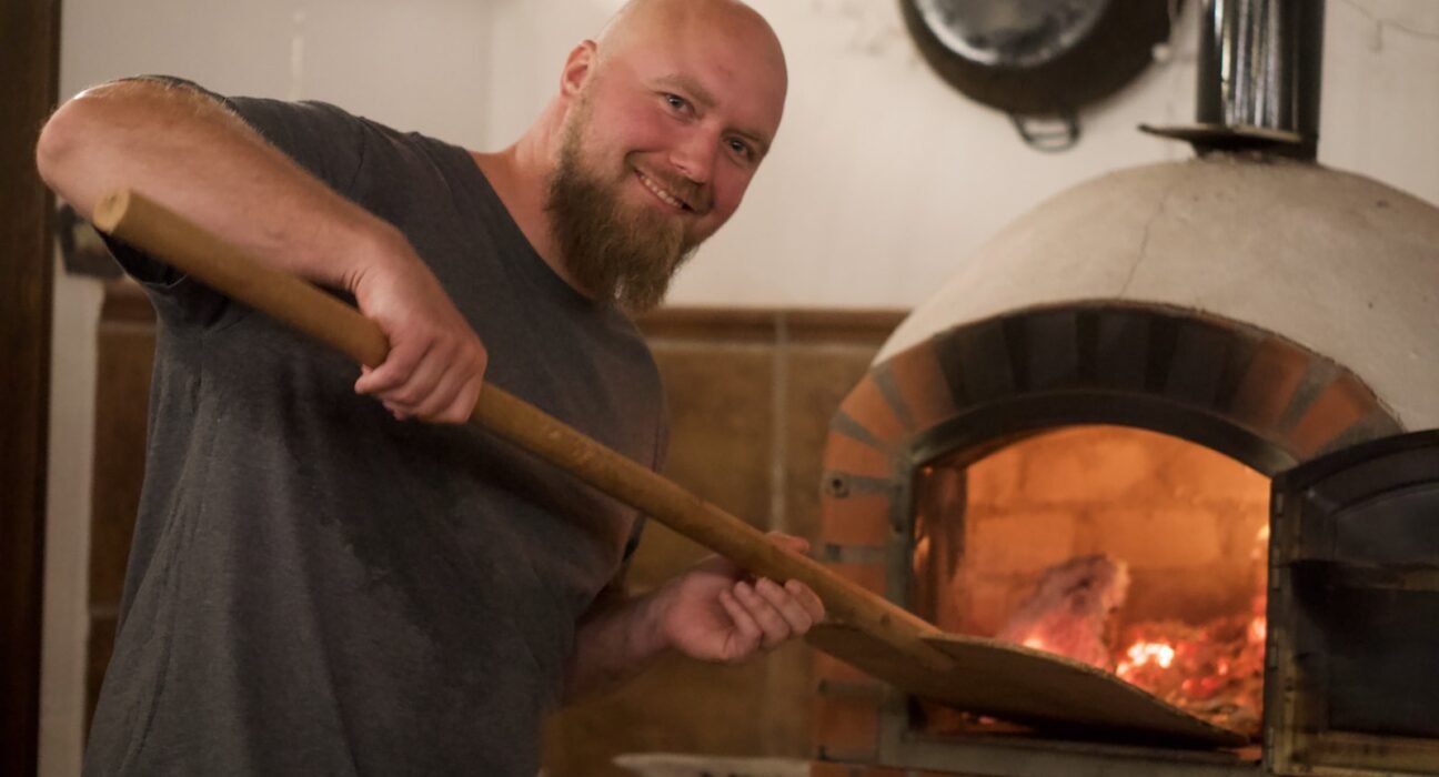 man in black crew neck t-shirt holding brown wooden stick