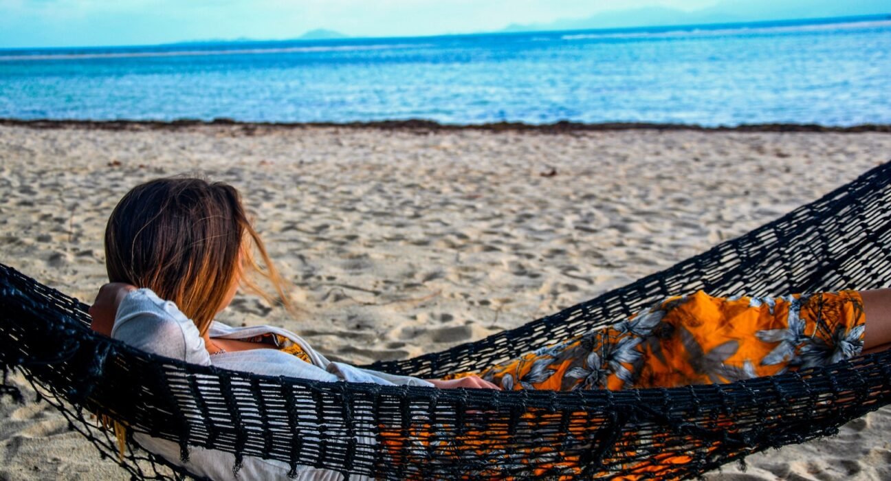 woman in white shirt lying on hammock on beach during daytime