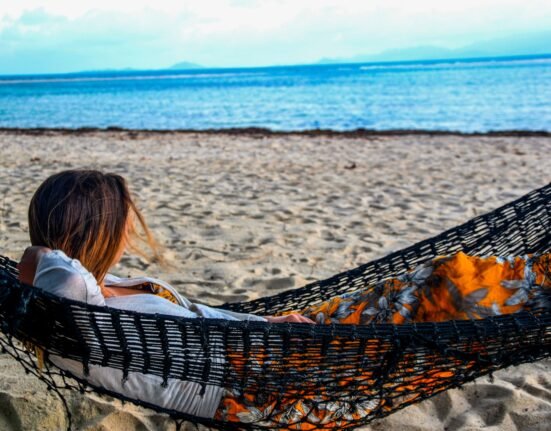 woman in white shirt lying on hammock on beach during daytime