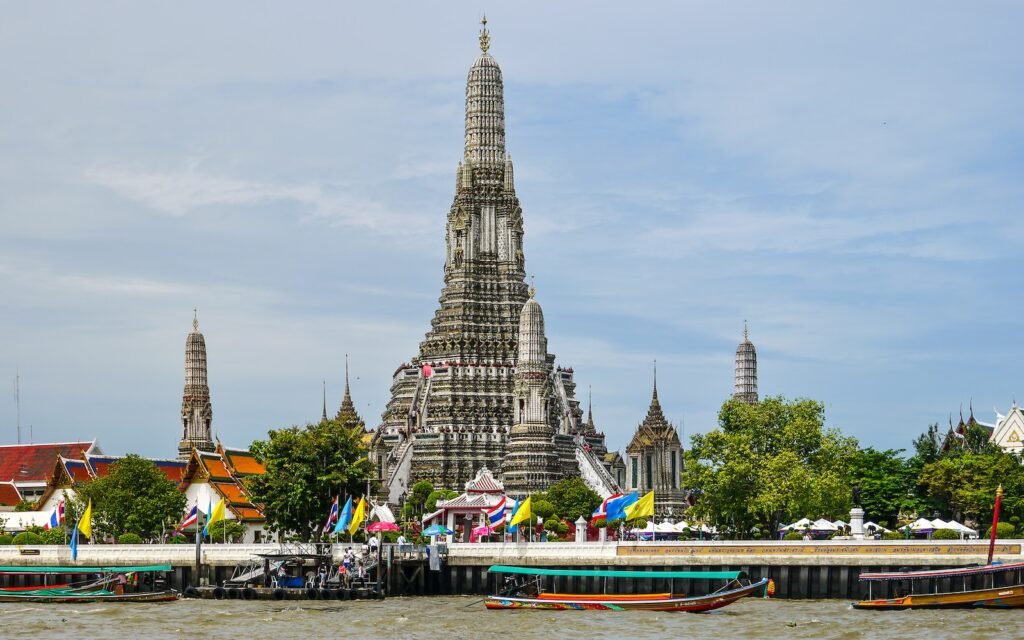 a large building with pointy towers with Wat Arun in the background