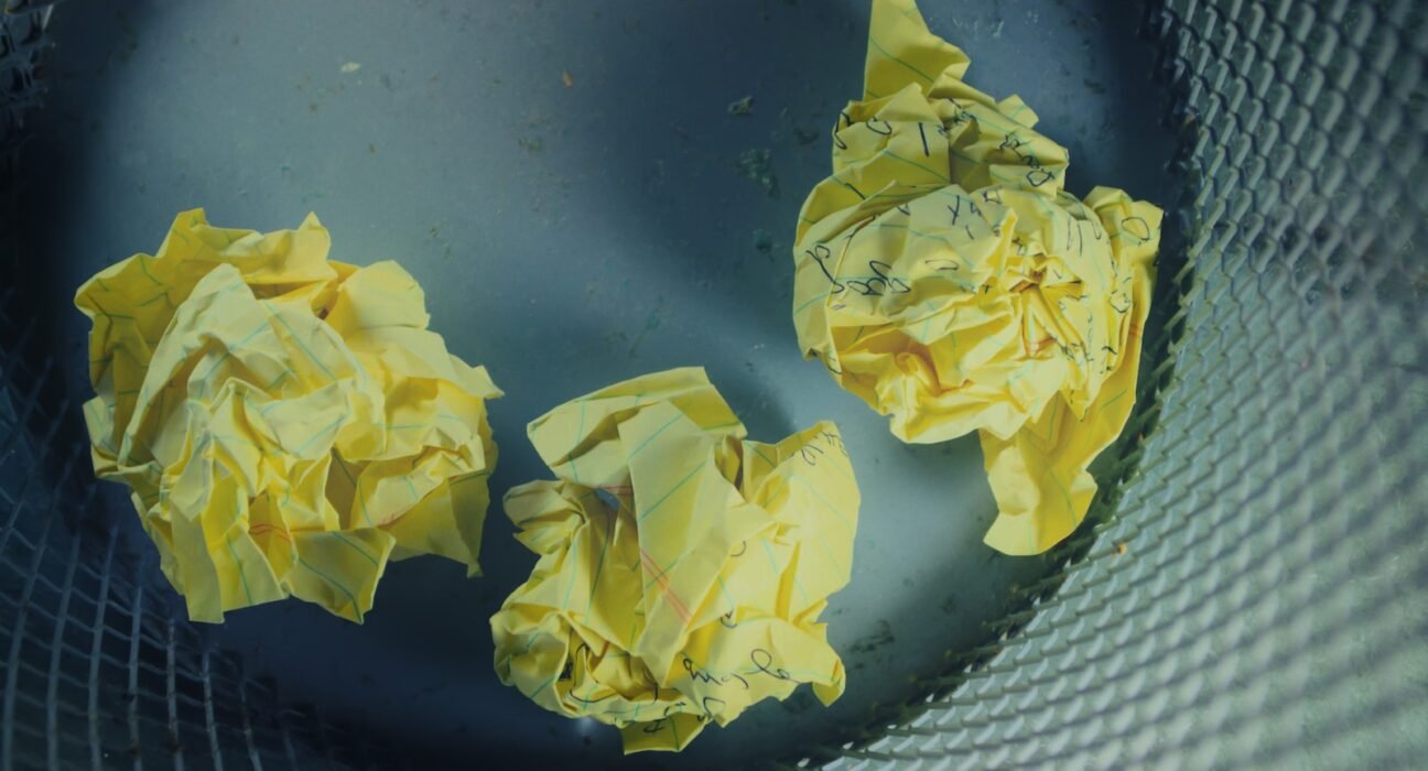 three yellow crumbled papers inside gray trash bin