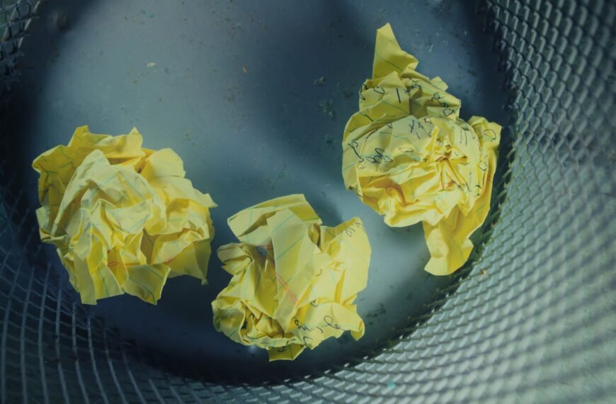 three yellow crumbled papers inside gray trash bin