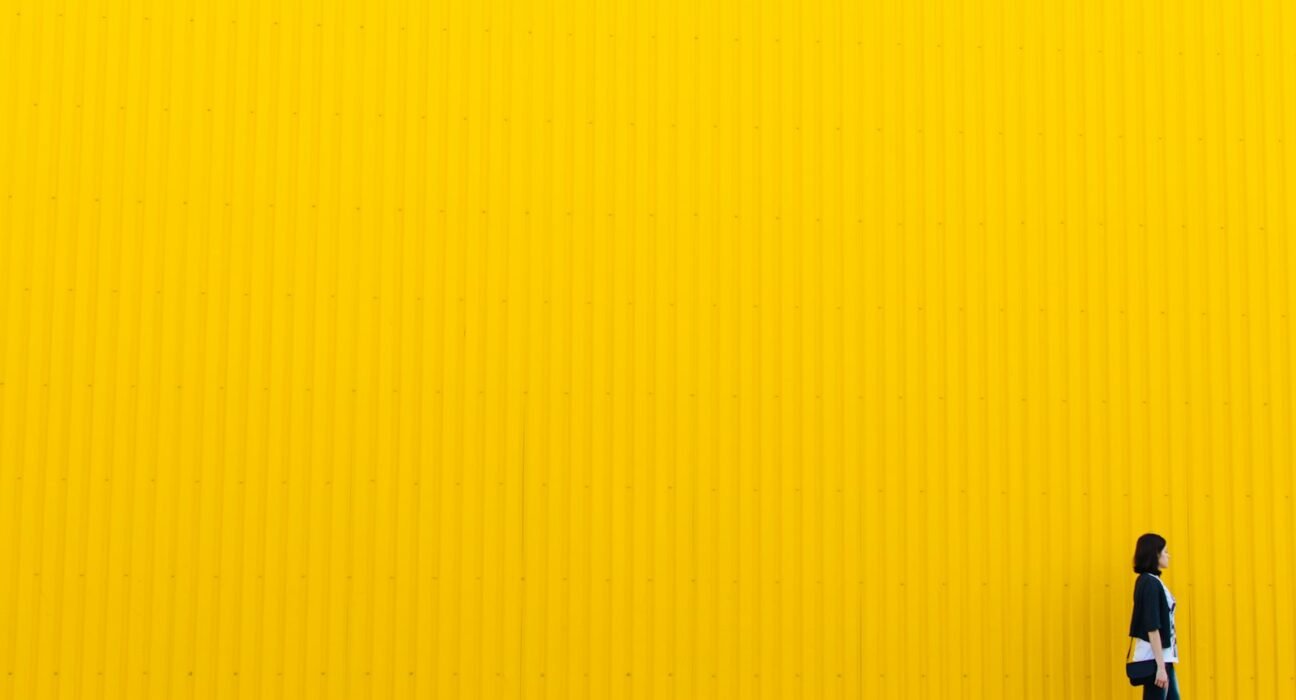 woman wearing black top standing near yellow wall