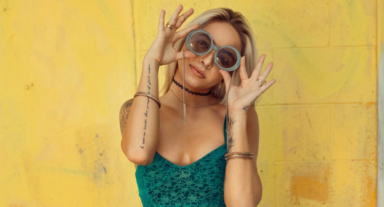 woman in blue bralette holding sunglasses putting on her eyes