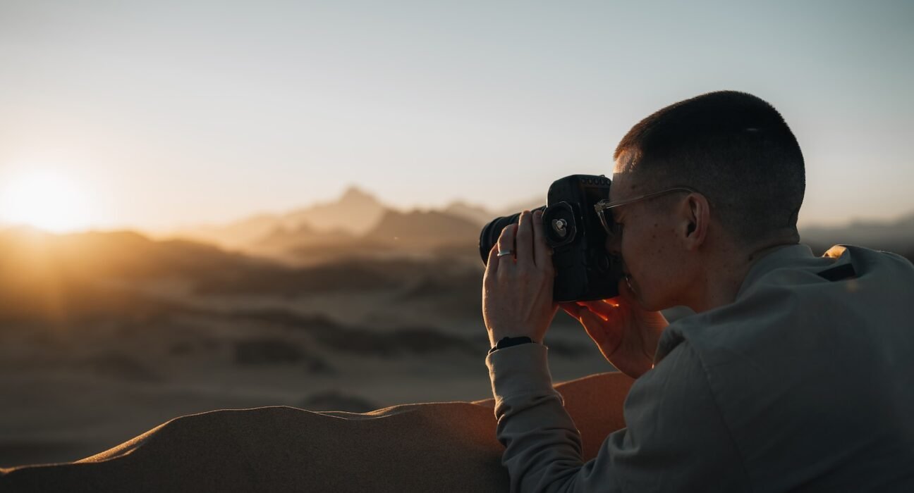 a man taking a picture of the sunset with a camera