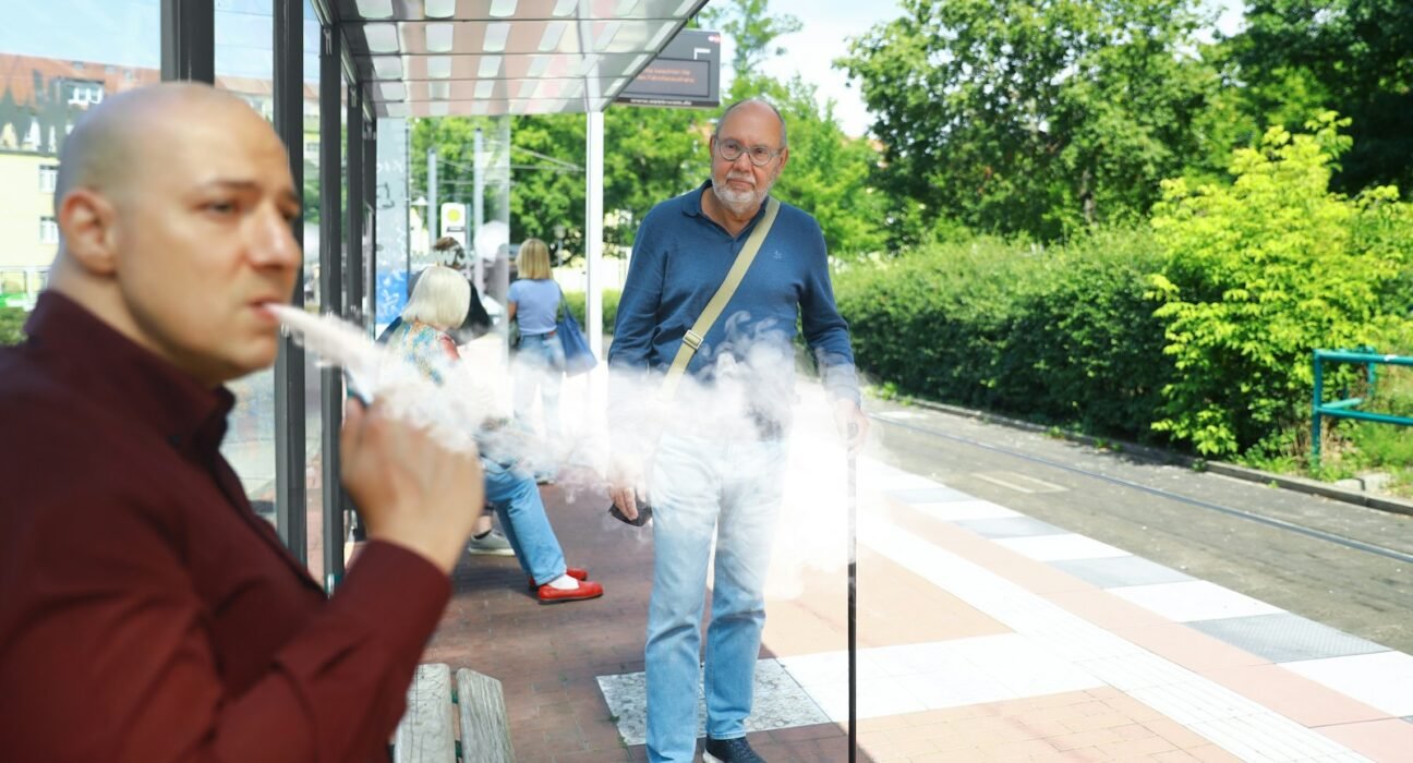 a man smoking a cigarette in front of a bus stop