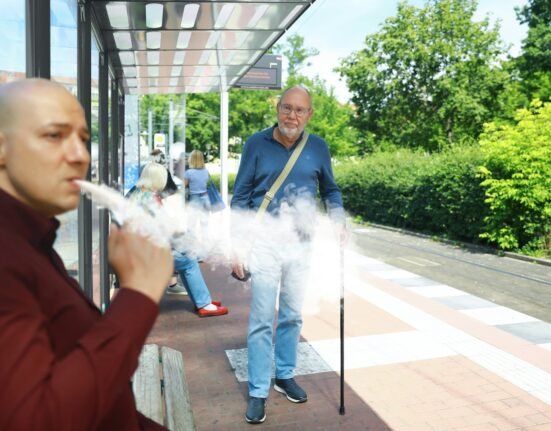 a man smoking a cigarette in front of a bus stop